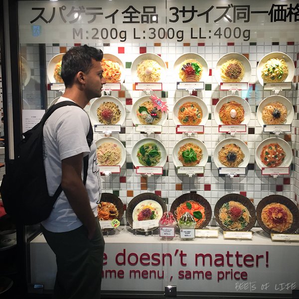 Tanuj standing in front of restaurant plastic food display